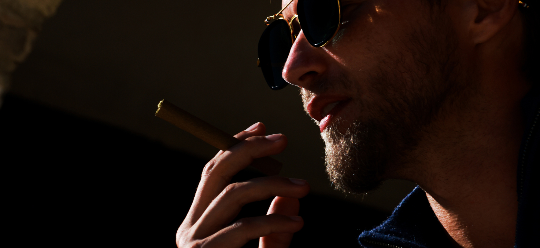 A man with a cigar in his mouth, exuding a relaxed and confident demeanor.