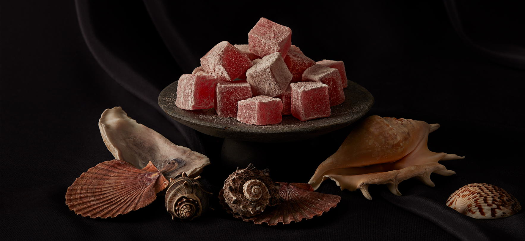 A bowl of red and white candies displayed on a black background, highlighting the vibrant colors of the sweets.