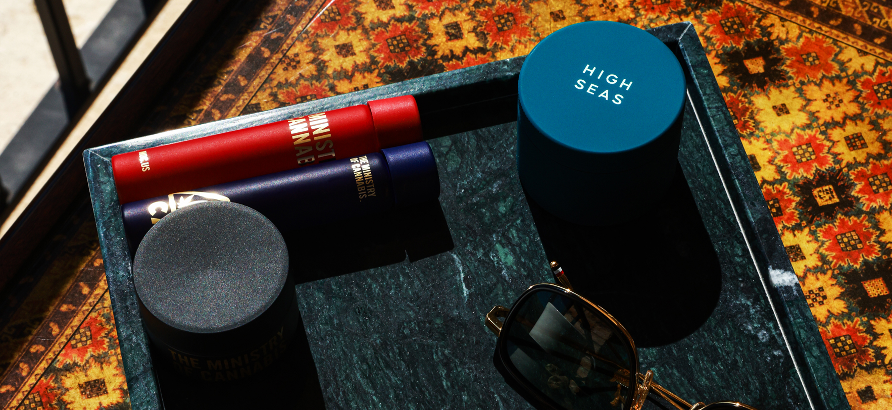 A tray displaying a pair of sunglasses, a red can, and a blue can arranged neatly