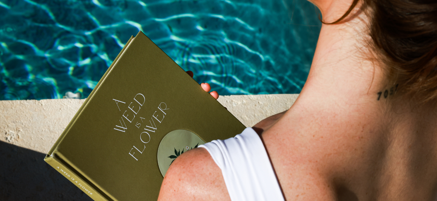 A woman relaxes by the pool, focused on a book in her hands