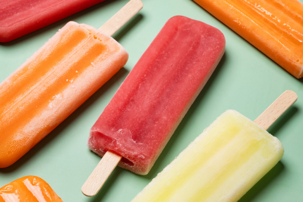 Red, orange, and yellow popsicles on a mint green background