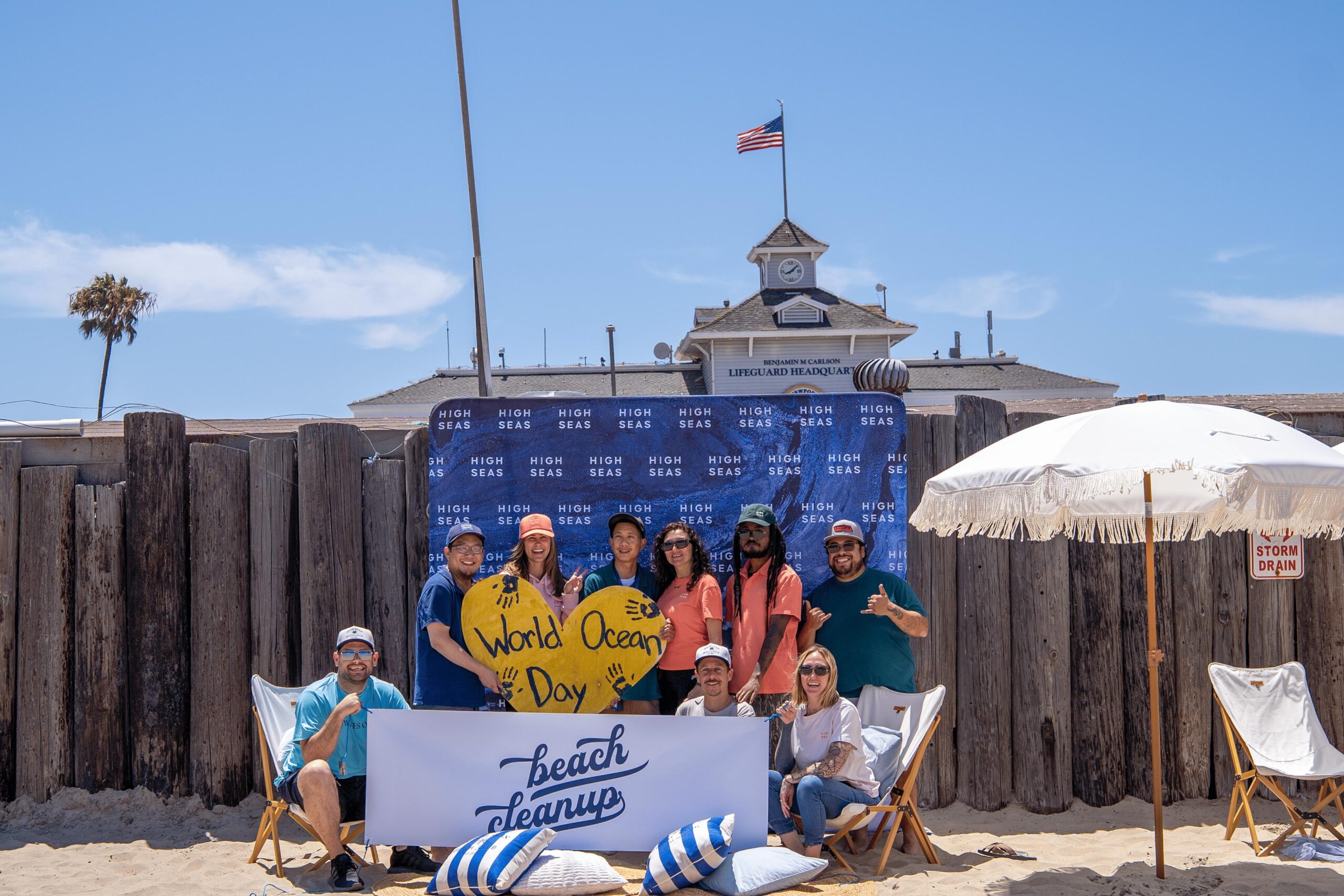High Seas team members posing at a World Ocean Day beach cleanup in front of the Newport Beach lifeguard headquarters.