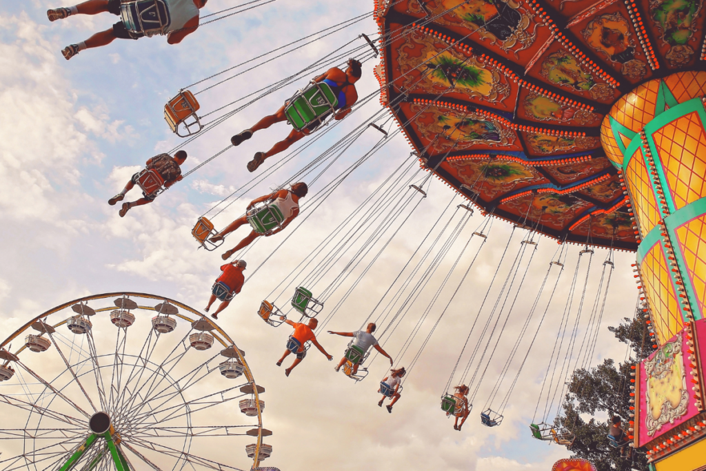 People riding a carnival swing attraction beside a Ferris wheel