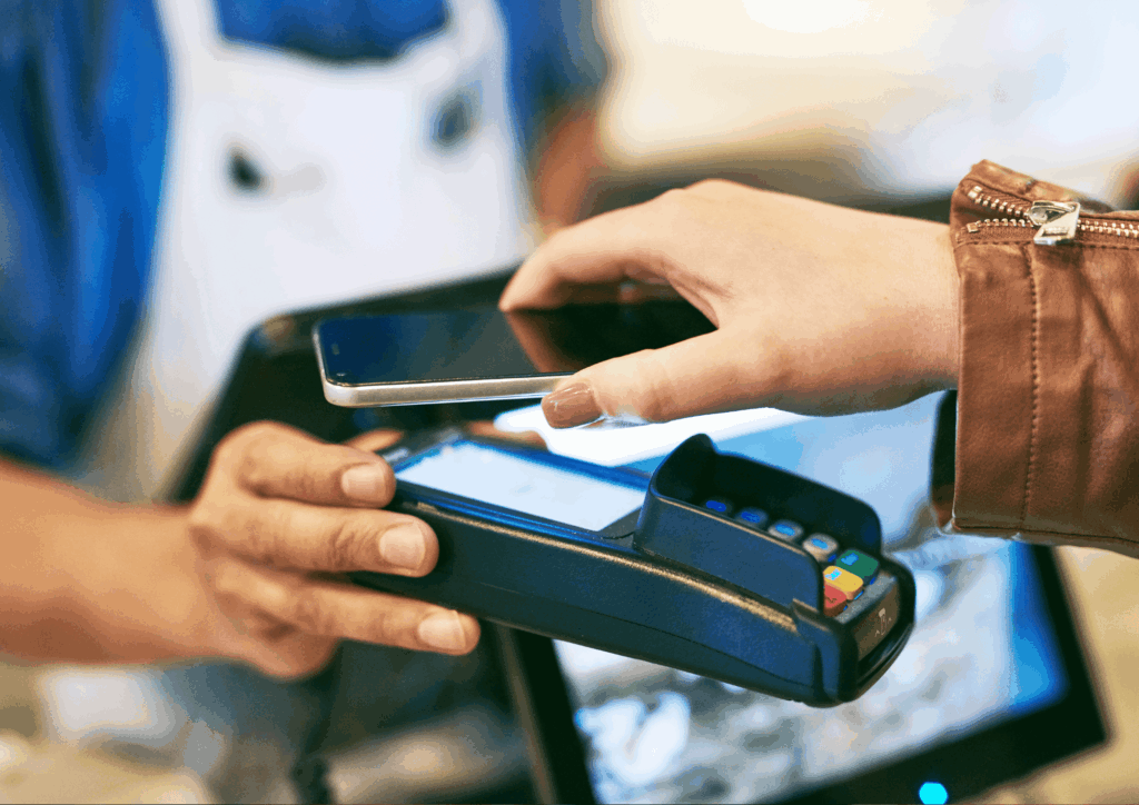 Customer holding a smartphone over a contactless payment terminal