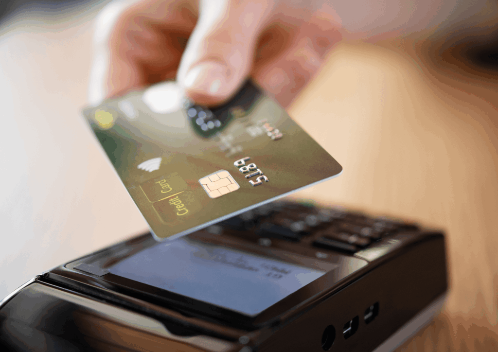 Hand holding a credit card above an electronic payment terminal