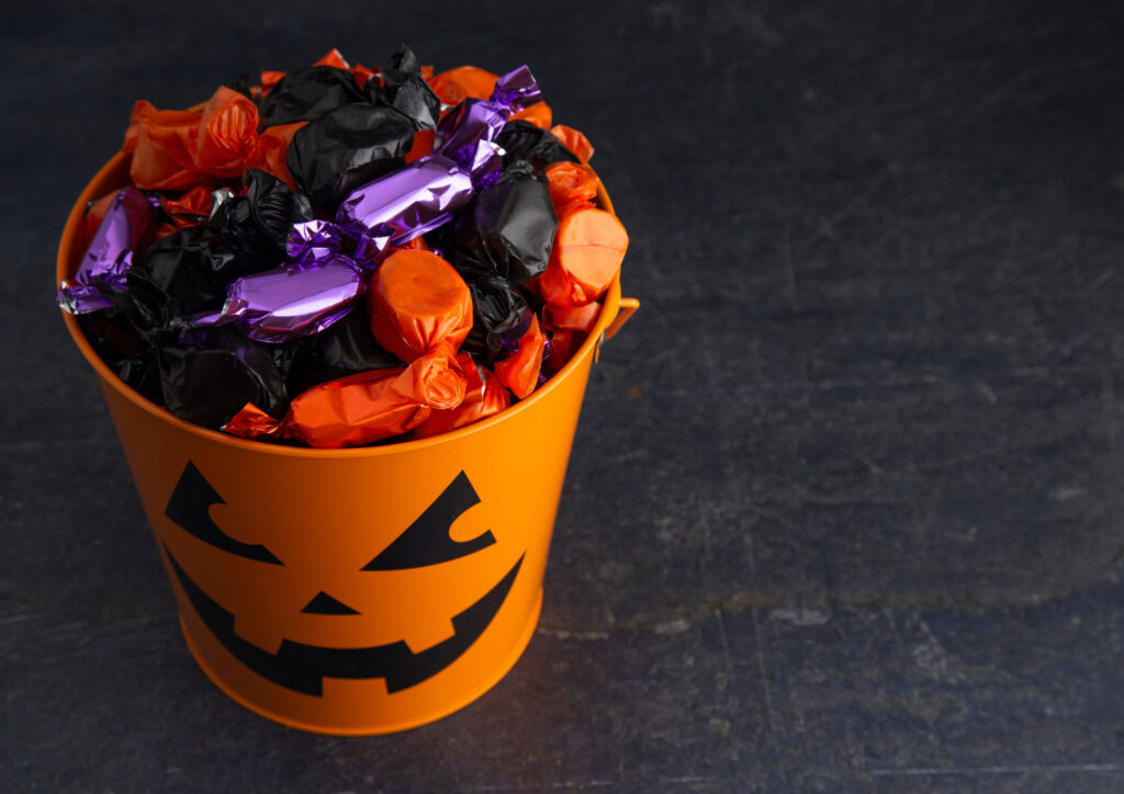 Orange jack-o’-lantern bucket filled with purple, orange, and black wrapped candy