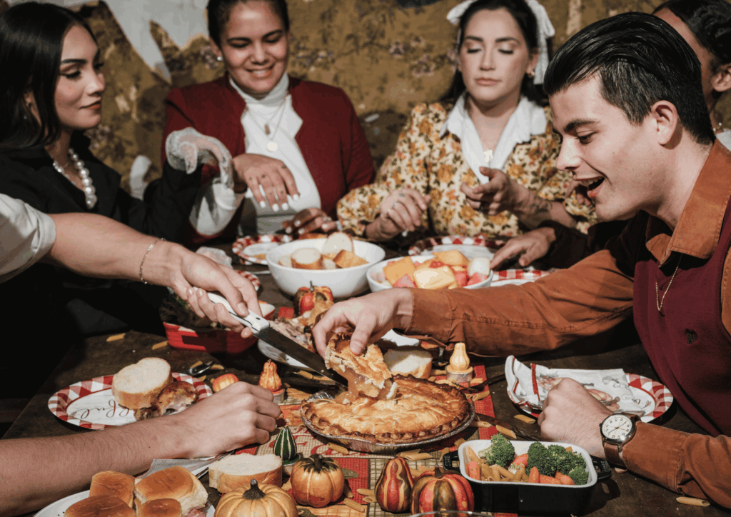 Group of adults serving pie and sharing food around a holiday dinner table